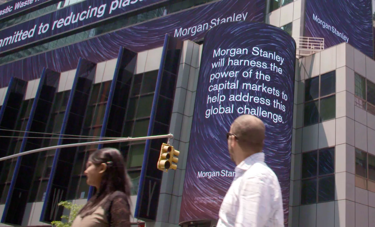 Passersby view the Morgan Stanley's digital screen at a street intersection, which reads, "Morgan Stanley will harness the power of capital markets to address this global challenge."