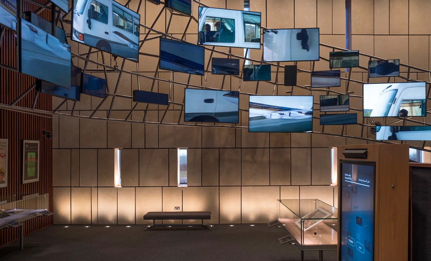 Series of digital screens are hung on metal scaffolding, displaying a montage of Arabic films.