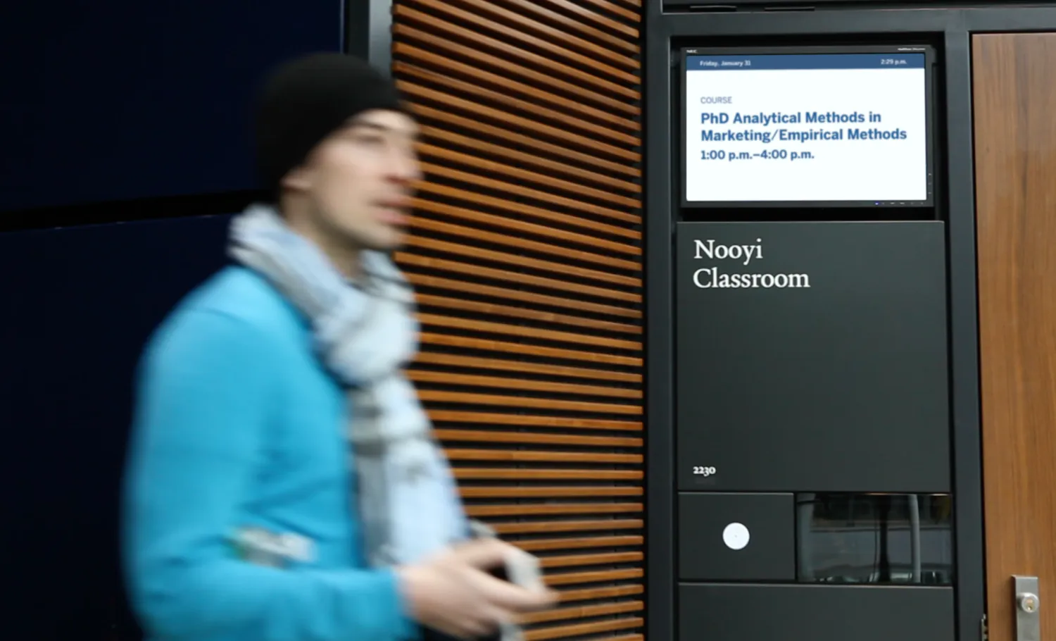 Student walking past a classroom with a digital signage in front showing real-time information.