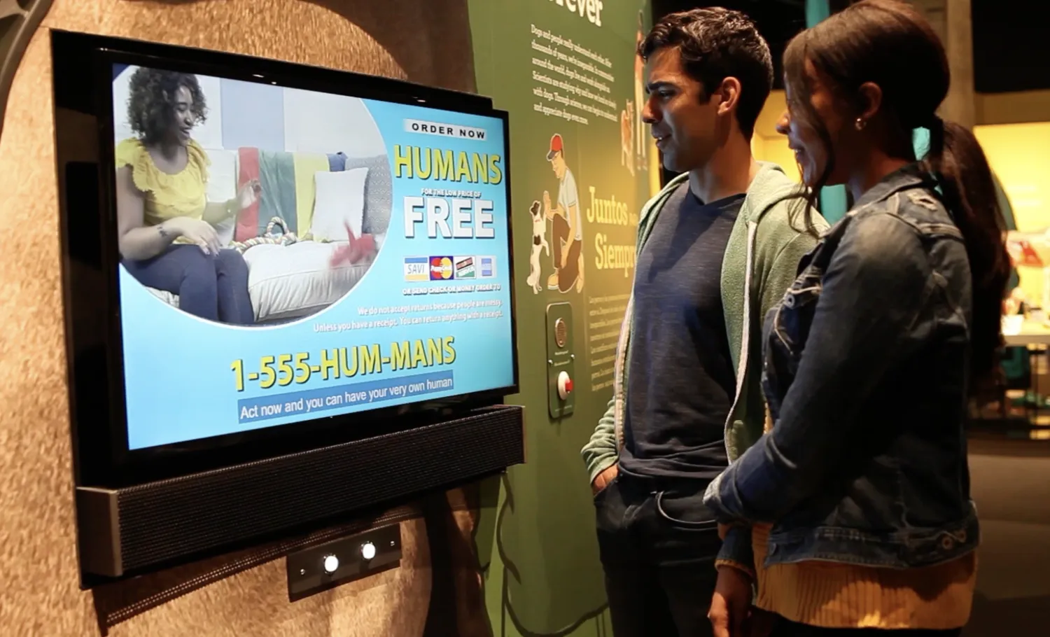 Visitors watching an infomercial on dog care on a digital screen.