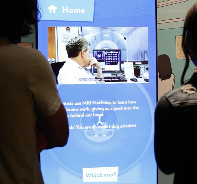 Visitors look at a digital screen showing information on how pet MRI's are conducted.