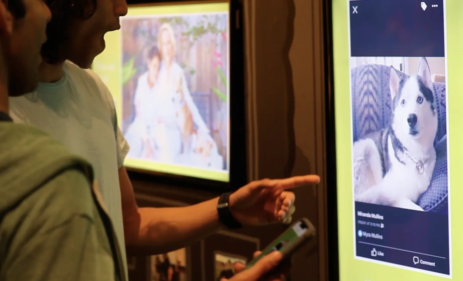 Visitors look and points at various visitors' pets images shared through the exhibition interactive.