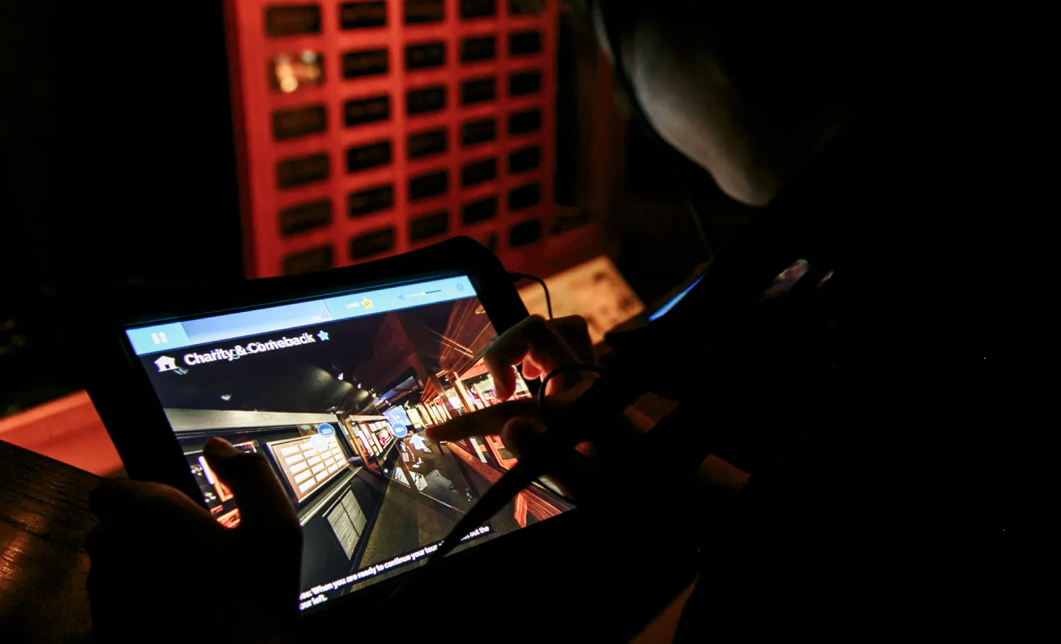 Visitor using a touchscreen tablet to look through media content and archival items.