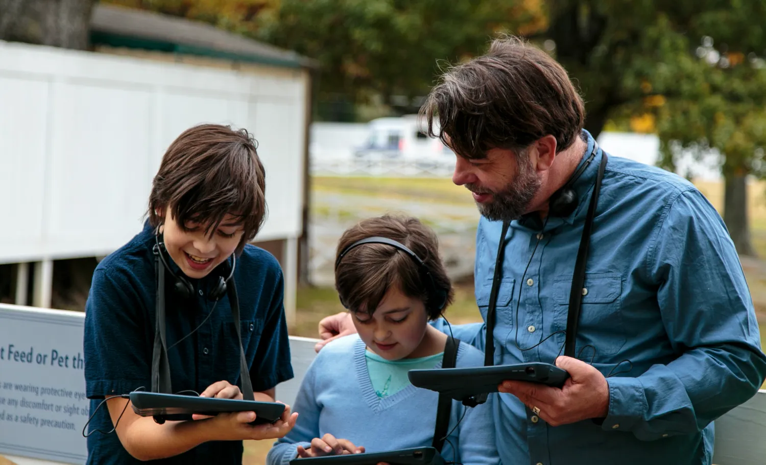 A family of visitors look at individual companion tablets together.