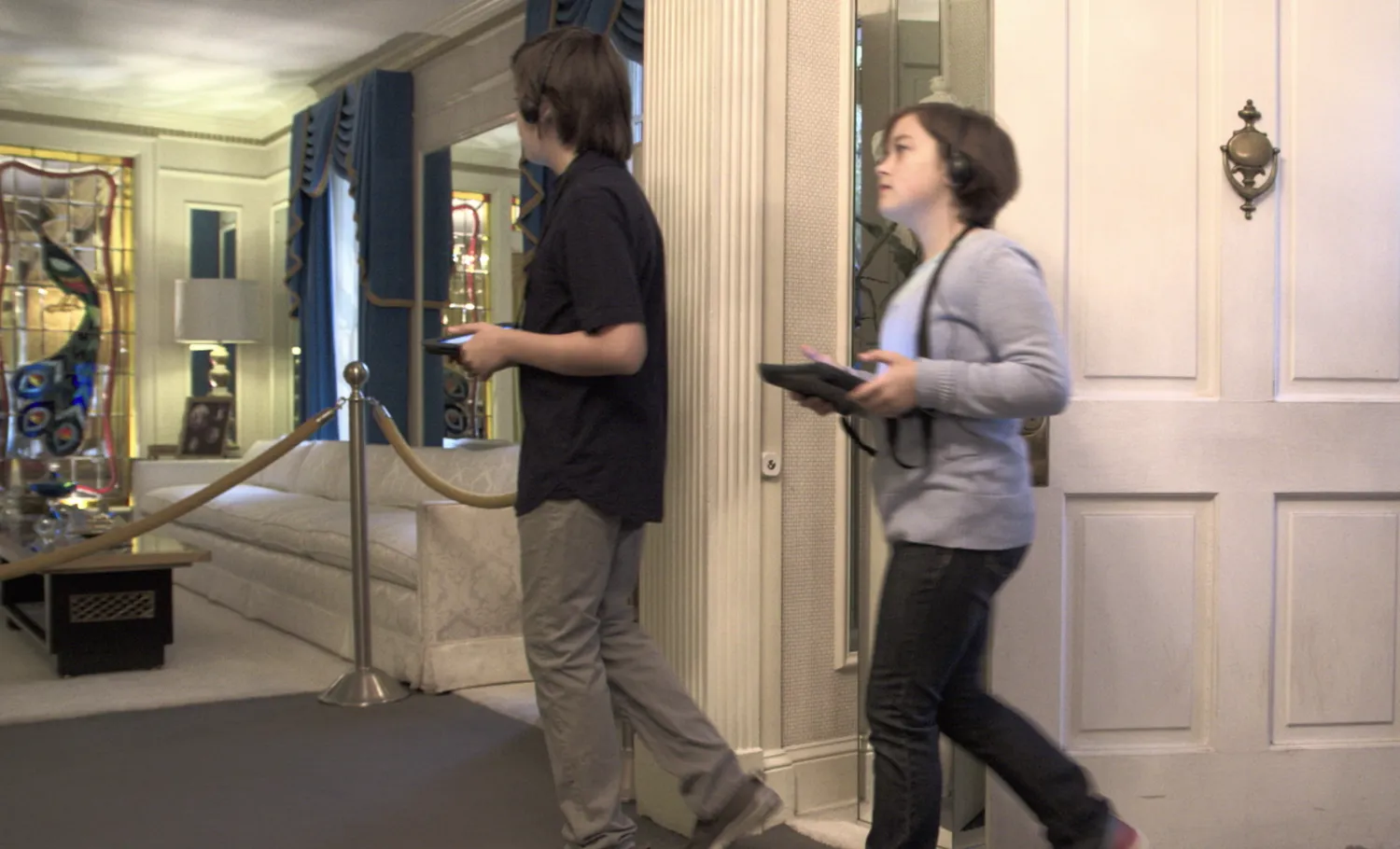 Visitors walkthrough the Graceland Mansion while holding a companion tablet guide.