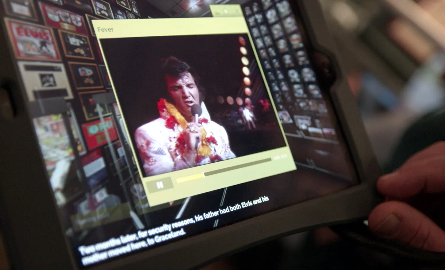 A digital touch screen shows a short Elvis Presley video on a media player.