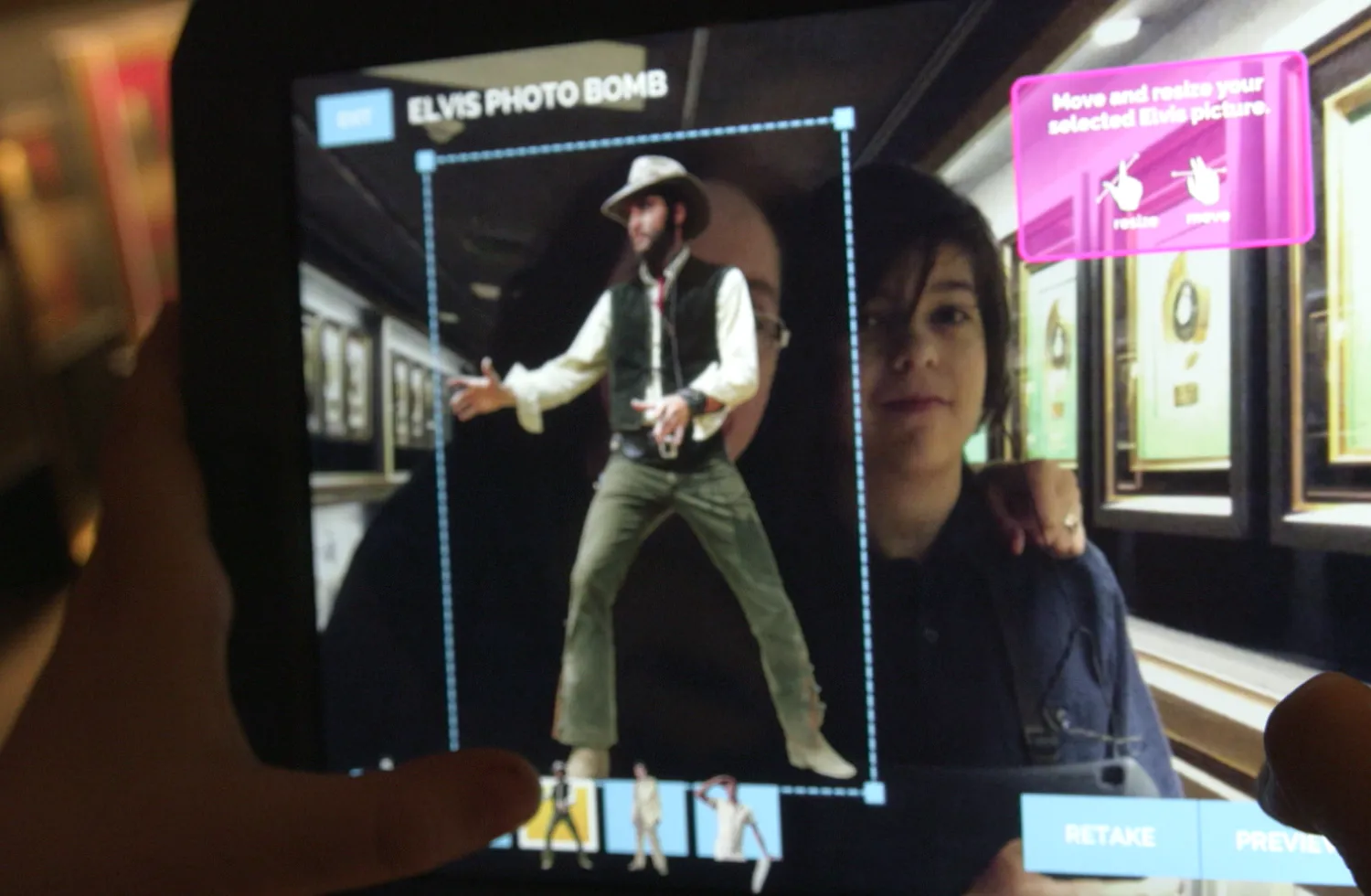 "Child and guardian uses the augmented reality camera application ""Elvis Photobomb"" on the companion tablet to include Elvis Presley in their photos.
"