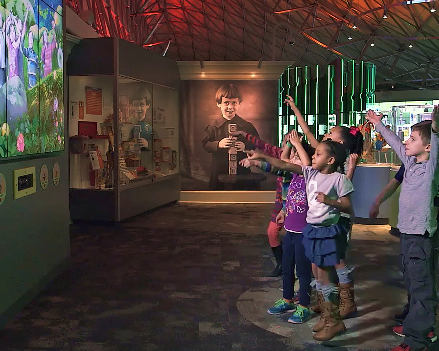 Children standing in front of a large vertical screen playing with a gesture-based game.
