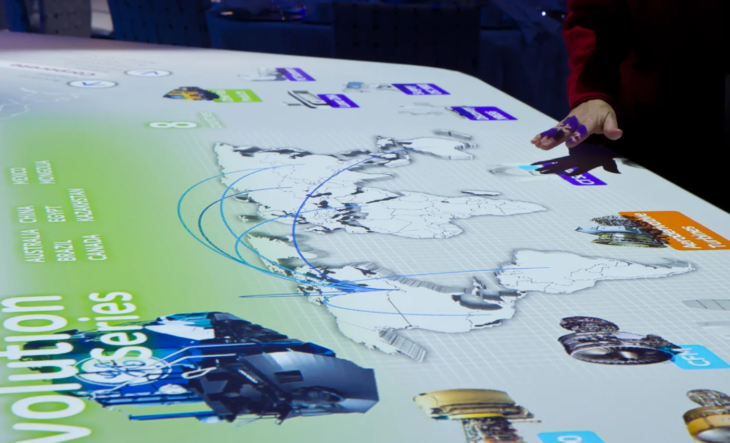 Visitor interacting with a large touch screen table showing GE's work across the globe.