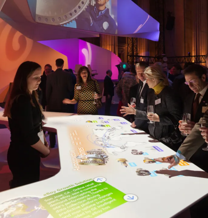 Visitors conversing with each other and interacting with a motion-sensored activity table.