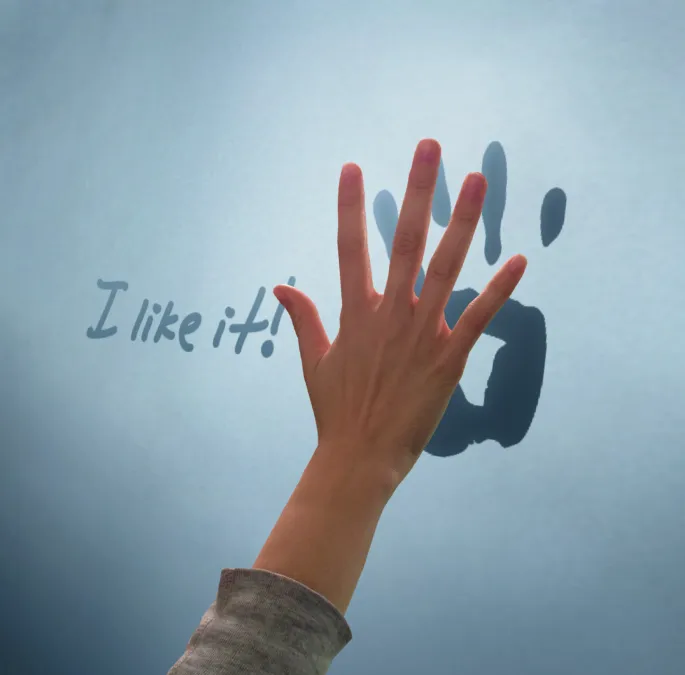 A hand reaches to interact with the digital immersive wall, which creates a digital handprint onto the wall. On-screen text reads: "I like it!"