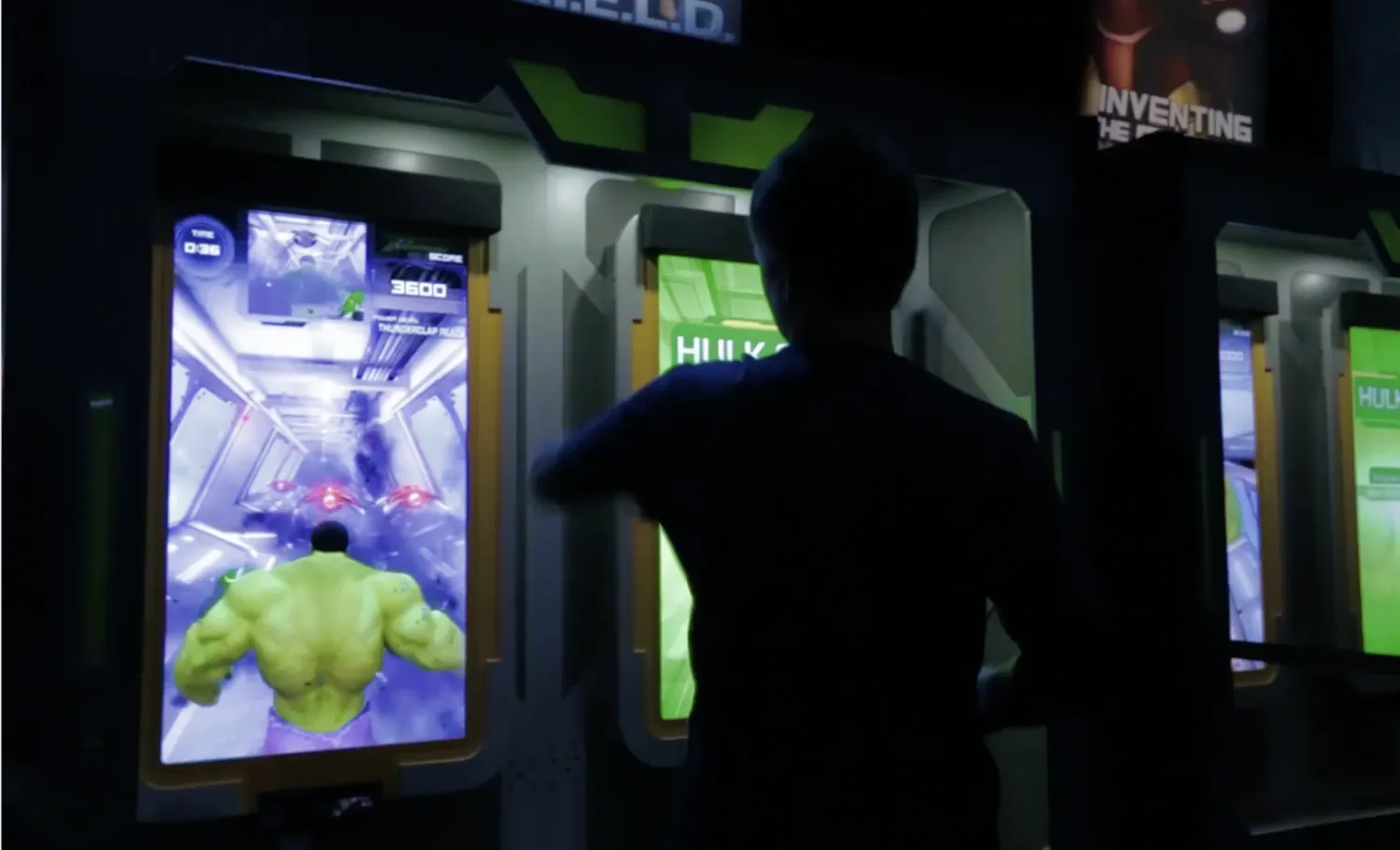 A visitor poses in front of a motion-based interactive depicting The Incredible Hulk walking through walls.