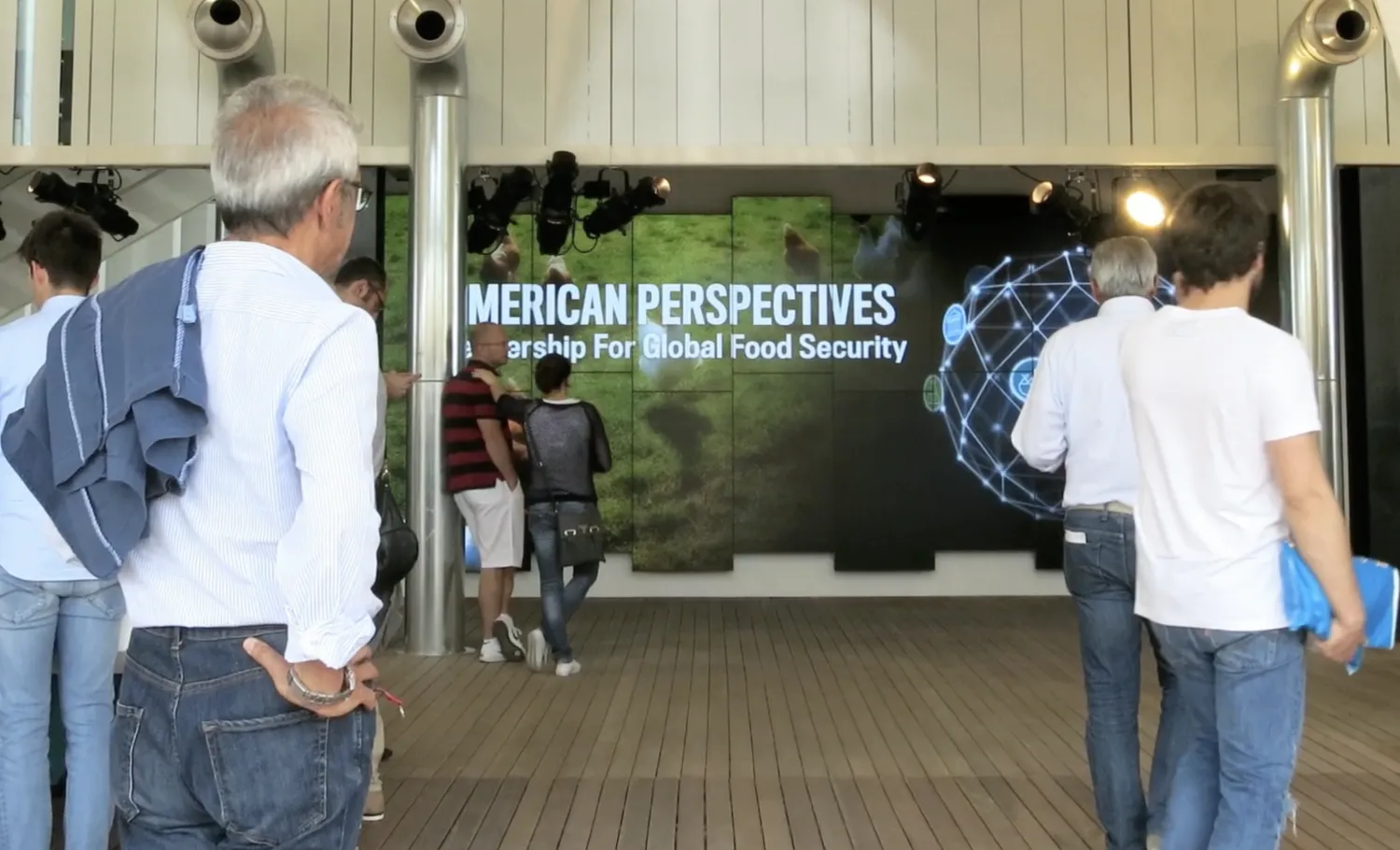 Visitors watch the large media wall playing an exhibition film titled, "American Perspectives: Leadership for Global Food Security".