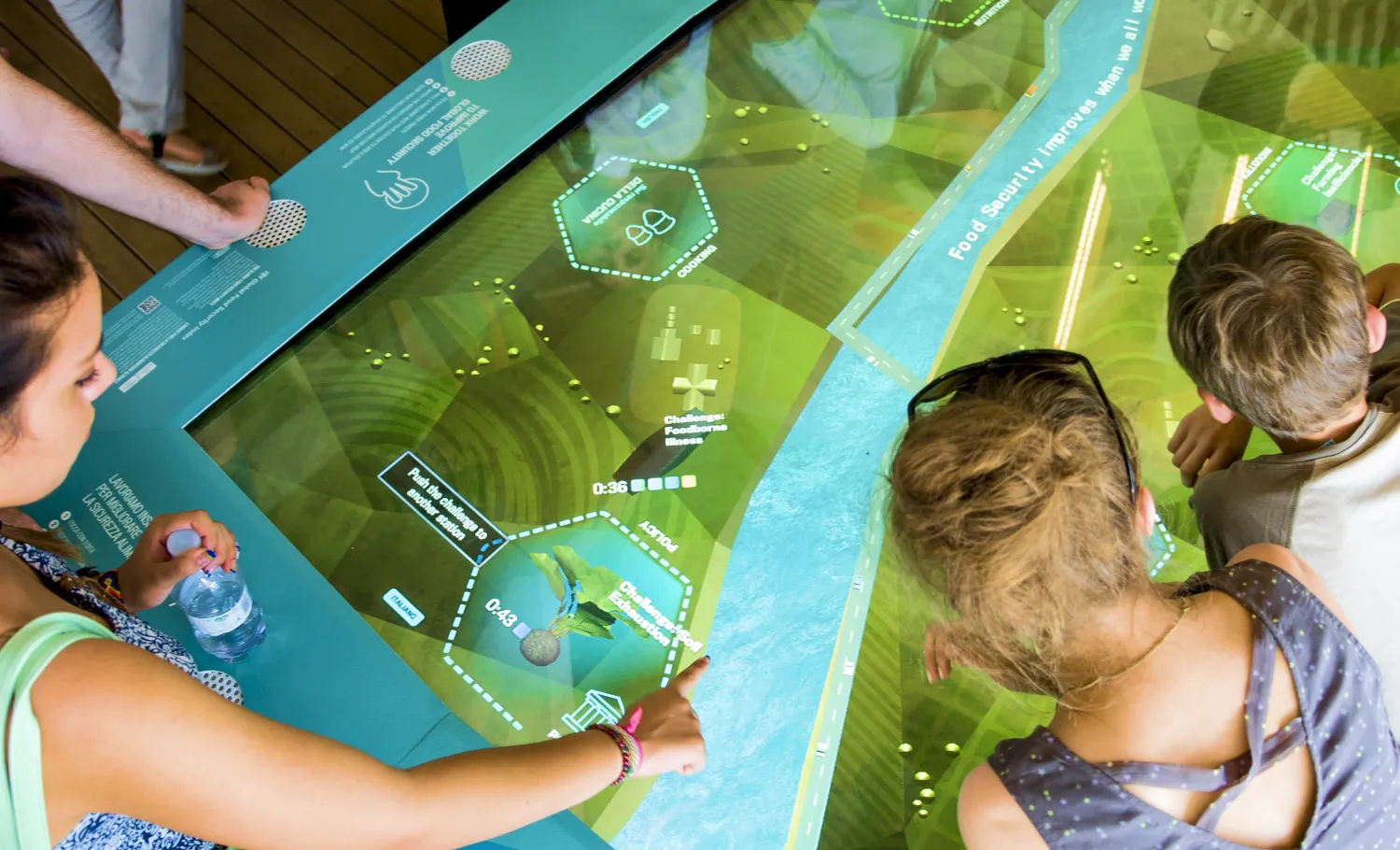 Visitors play with a food security-related interactive on an activity table.