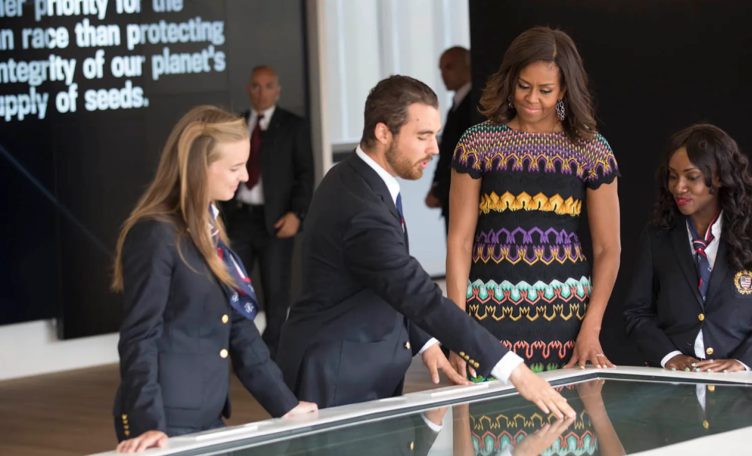 Exposition staff introduces the interactive table to former First Lady Michelle Obama.