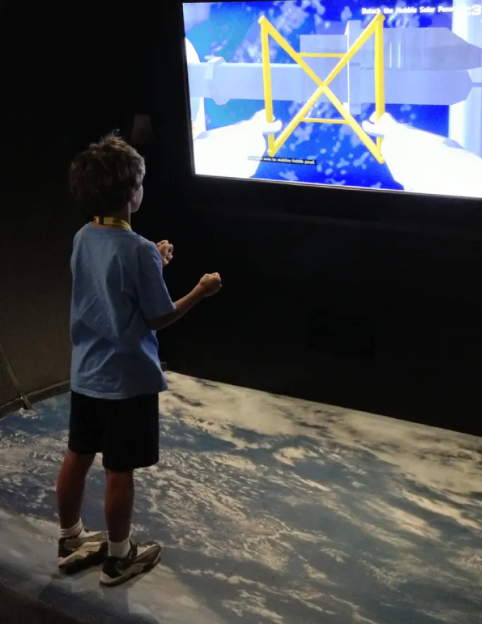 Young child plays with a gesture-based space shuttle landing simulator.